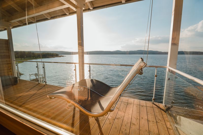 Blick auf eine Doppelhängeliege und den See auf dem Balkon des Luxus Refugium