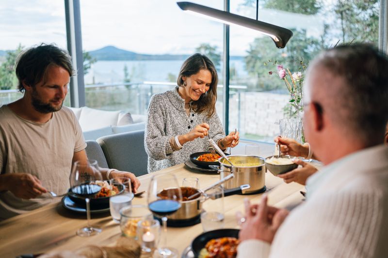Gruppe am Esstisch beim Abendbrot mit Sonnengang im Hintergrund und Blick auf den See