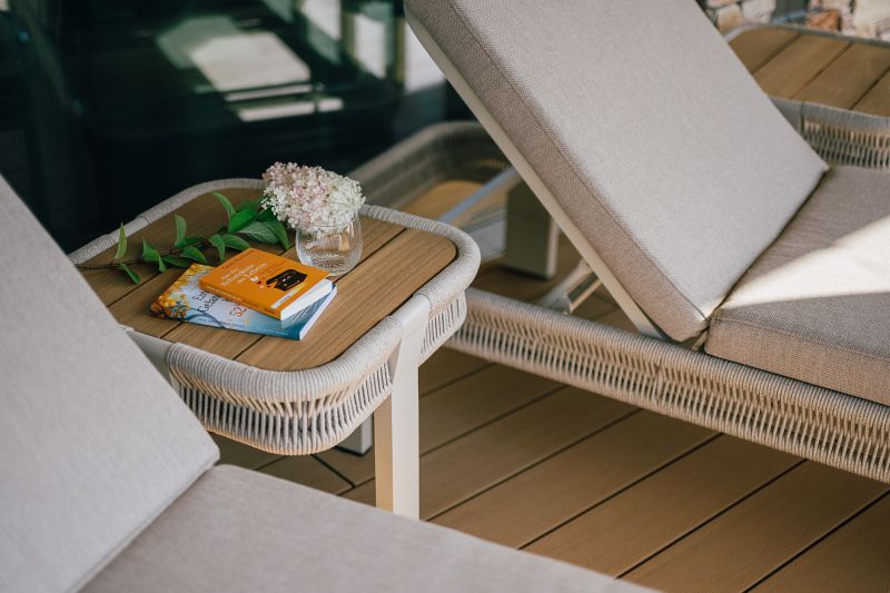 Detailfoto Liegestühle und Beistelltisch mit Blumen und Büchern