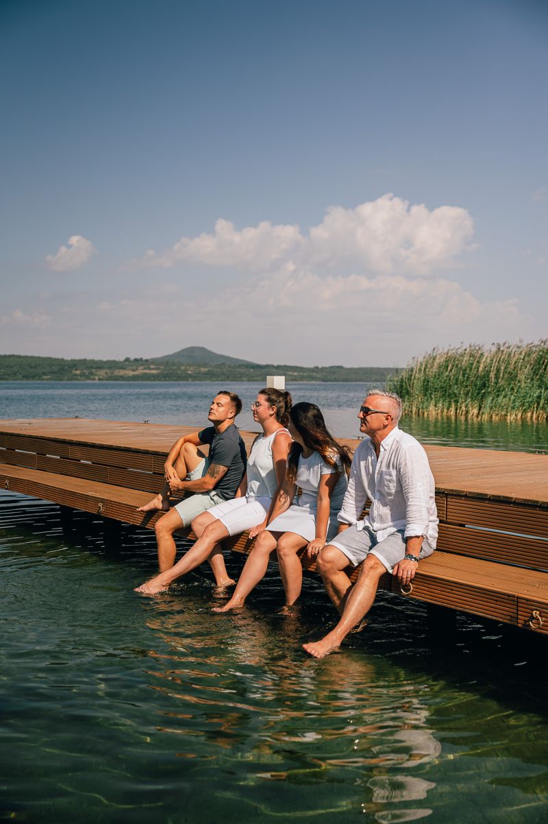 Gruppe sonnt sich auf dem Steg mit den Füßen im Wasser