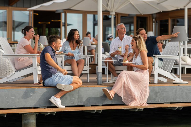 Kleine Gruppe sitzt auf der Restaurantterrasse nah am Wasser