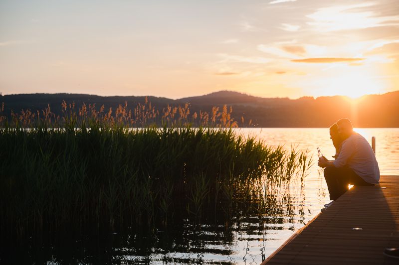 Pärchen sitzt auf dem Steg bei Sonnenuntergang
