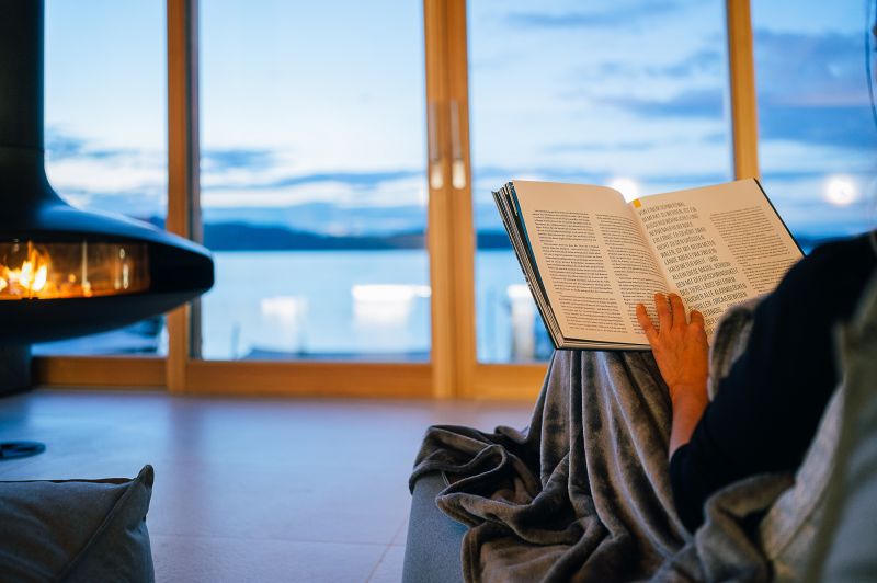 eine Person liegt am Kamin im Ruheraum 'Raum der Luft' und liest